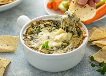 su base grigia una teglia tonda con dentro la parmigiana di carciofi