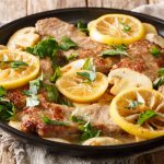 Scaloppine al limone: la ricetta semplice e veloce passo passo 1 scaloppine al limone su un piatto tondo nero con fette di limone