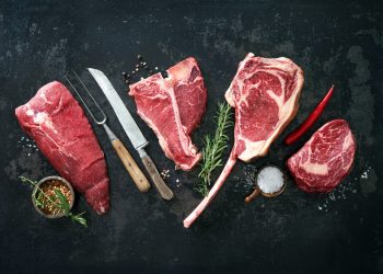 alcuni tagli di carne di manzo su un tavolo con accanto dei coltelli