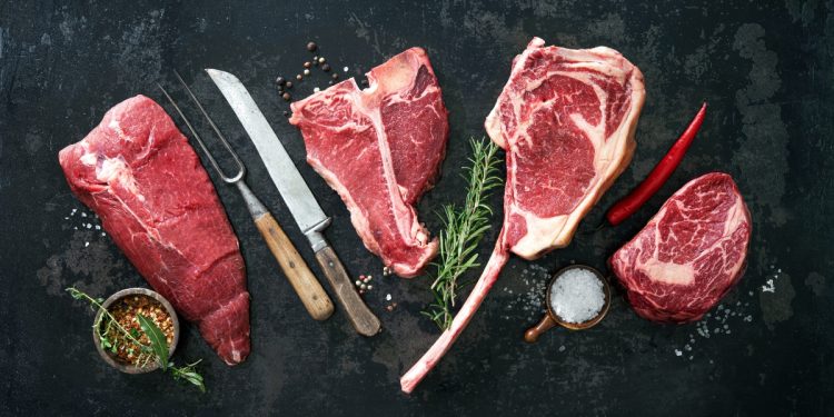 alcuni tagli di carne di manzo su un tavolo con accanto dei coltelli
