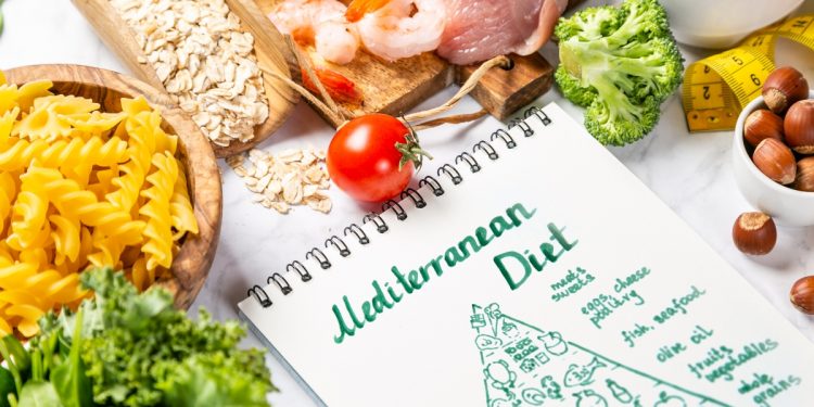 alcuni cibi come pasta, pesce e verdure su una tavola con in primo piano un'immagine della piramide alimentare