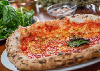 Su tavolo di legno primo piano di piatto con la pizza marinara e origano