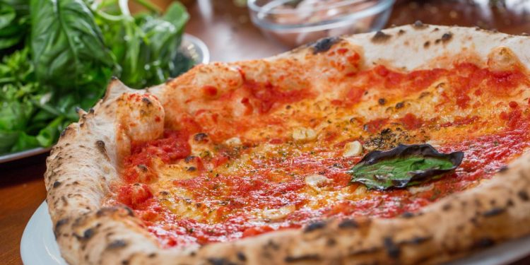 Su tavolo di legno primo piano di piatto con la pizza marinara e origano