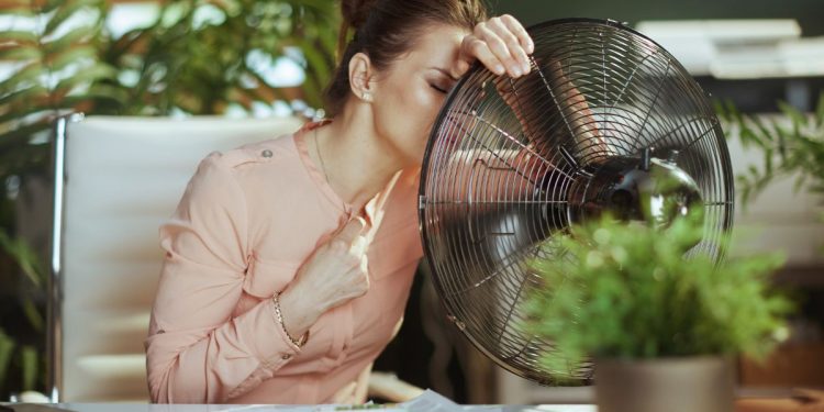 una donna accanto a un ventilatore in un ambiente di ufficio