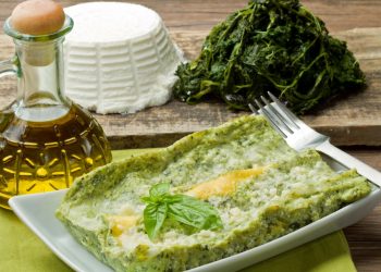piatto rettangolare con una porzione di lasagna, oliera, ricotta e spinaci accanto
