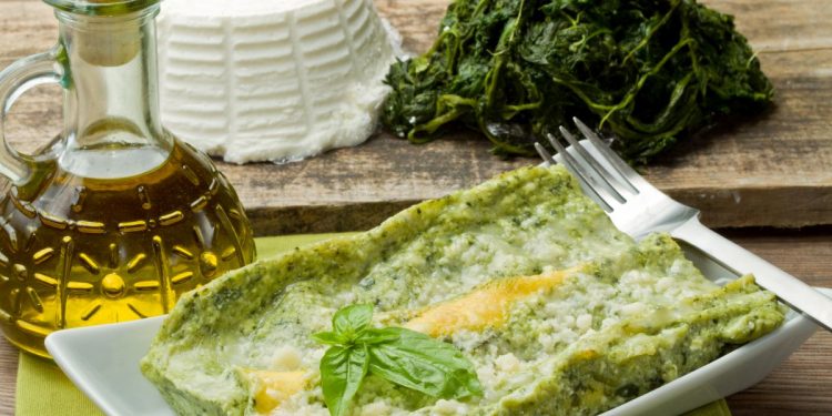 piatto rettangolare con una porzione di lasagna, oliera, ricotta e spinaci accanto
