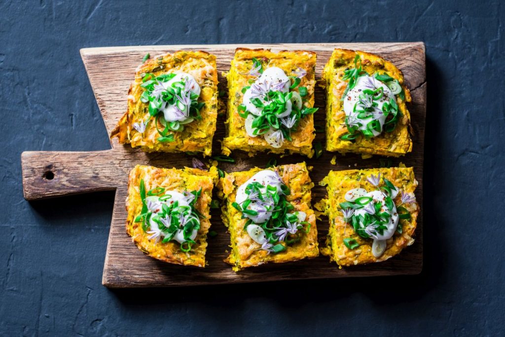 ricette con frittata: su tagliere di legno 6 tranci di frittata son sopra le verdure