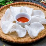 Come preparare le nuvole di drago: ricetta facile e croccante 1 vassoio tondo di bambù con nuvole di drago bianche e una ciotola di salsa piccante al centro