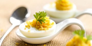 quante uova a settimana: metà uovo sodo su un cucchiaio in ceramica
