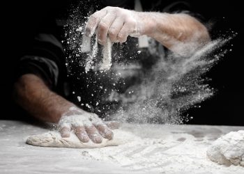 in primo piano delle mani che impastano e usano la farina di frumento