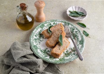 tavola con piatto con 3 fette di polpettone di tonno e canovaccio e olio d'oliva