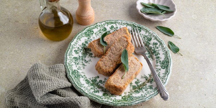 tavola con piatto con 3 fette di polpettone di tonno e canovaccio e olio d'oliva