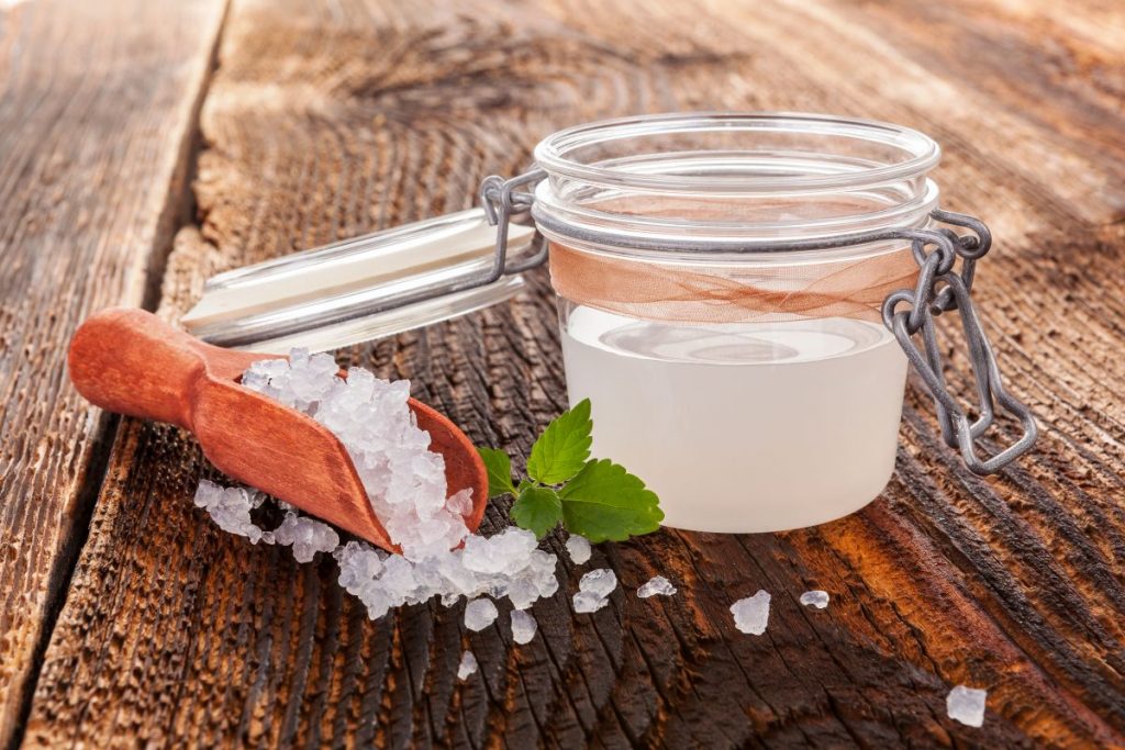Kefir d'acqua: come farlo a casa e quali sono i benefici 4 su tavolo di legno, contenitore di vetro ermetico con kefir d'acqua e accanto granuli per fare la ricetta in casa
