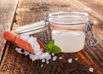 su tavolo di legno, contenitore di vetro ermetico con kefir d'acqua e accanto granuli per fare la ricetta in casa