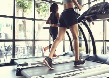 Gambe di una donna con gli shorts che si allena in palestra su un tapis roulant elettrico