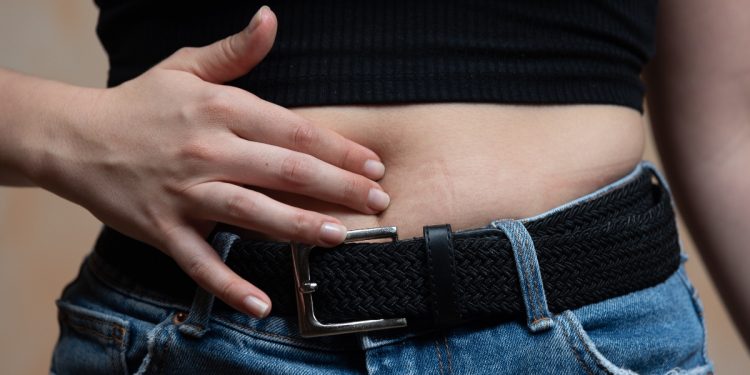 una donna che soffre di intolleranza alimentare che si massaggia la pancia posta in primo piano