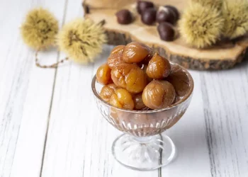 coppa di vetro con marron glaces e dietro vassoio di castagne