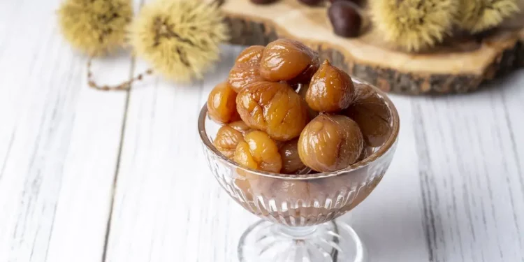 coppa di vetro con marron glaces e dietro vassoio di castagne