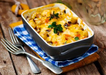 teglia con la parmigiana di zucca, due forchette e tovagliolo a quadri