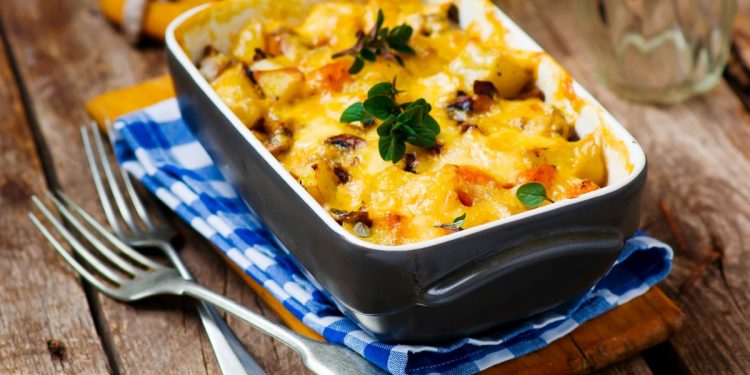 teglia con la parmigiana di zucca, due forchette e tovagliolo a quadri