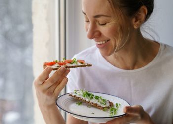 una donna con un piatto e due fette di pane con formaggio e verdure