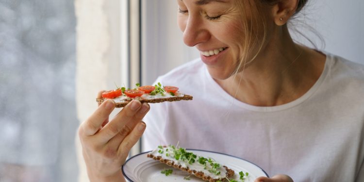 una donna con un piatto e due fette di pane con formaggio e verdure