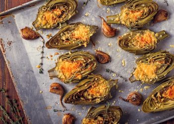 carciofi: una teglia coperta da carta forno con sopra tanti carciofi tagliati a metà e gratinati