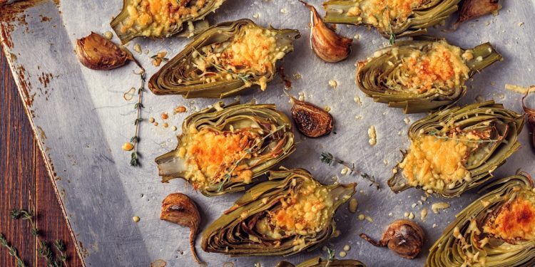 carciofi: una teglia coperta da carta forno con sopra tanti carciofi tagliati a metà e gratinati