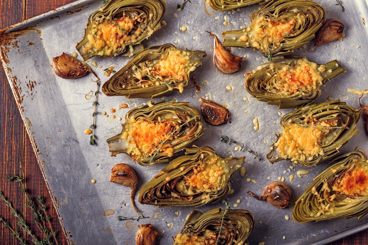 carciofi: una teglia coperta da carta forno con sopra tanti carciofi tagliati a metà e gratinati