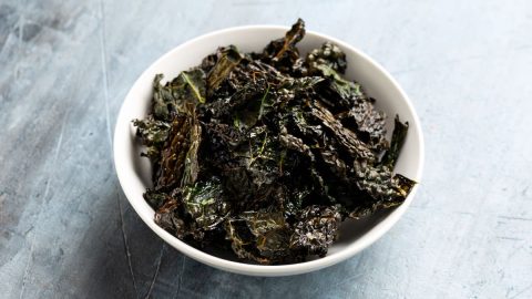 In primo piano in una ciotola bianca delle chips di cavolo nero gustose e croccanti.