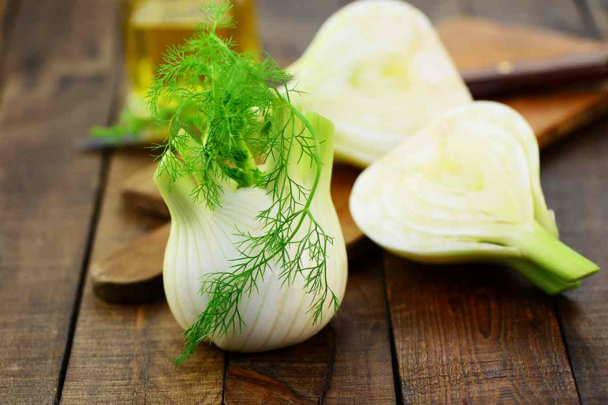 un finocchio intero e uno tagliato a metà su un tavolo di legno