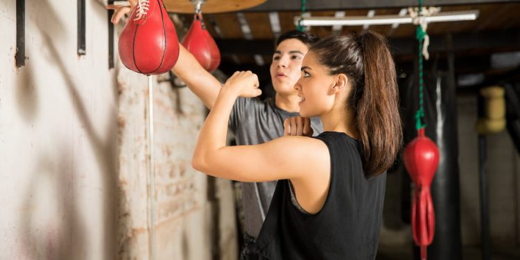 donna in palestra si allena con il pungiball o punching ball con il suo coach che gli spiega come fare