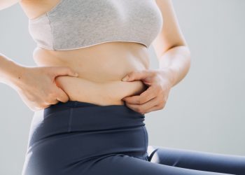 Donna in sovrappeso seduta che si tiene in mano il grasso addominale