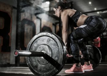 donna in palestra si allena con un bilanciere