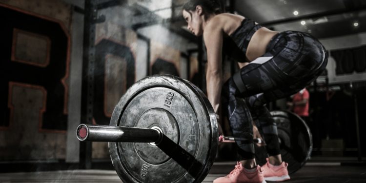 donna in palestra si allena con un bilanciere