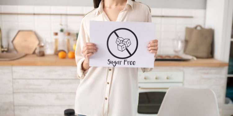 una donna in cucina mostra un cartello con scritto sugar free