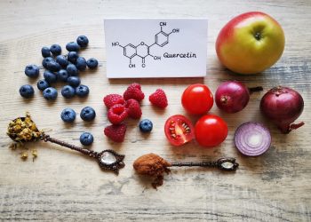 Mirtilli, lamponi, pomodorini, una mela, cipolle, spezie su una base di legno