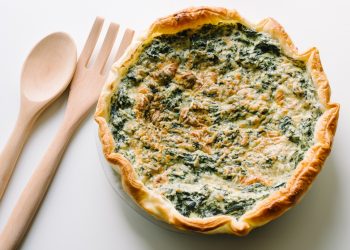 una torta ricotta e spinaci con due mestoli di legno accanto