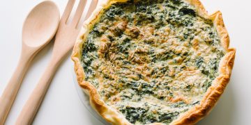 una torta ricotta e spinaci con due mestoli di legno accanto
