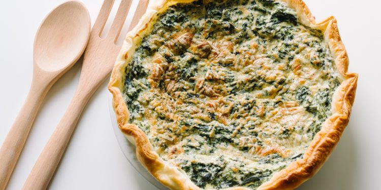 una torta ricotta e spinaci con due mestoli di legno accanto