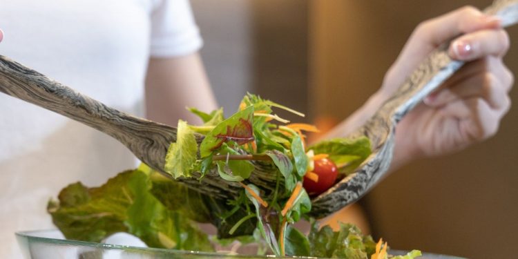 primo piatto della mani di una donna che mescola l'insalata per seguire una dieta ipocalorica