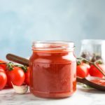 Passata di pomodoro fatta in casa facile e vellutata 1 Barattolo di passata di pomodoro fatta in casa con pomodori freschi sullo sfondo.