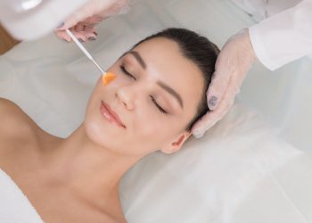 una donna a occhi chiusi su un lettino durante un trattamento estetico al viso