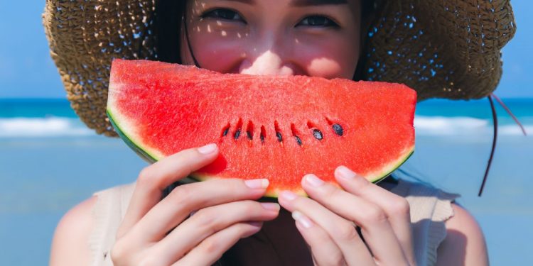 Una giovane donna che tiene in mano una fetta di cocomero