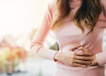 una donna che si tocca con entrambe le mani lo stomaco perché soffre di gastrite
