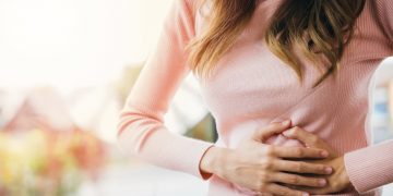 una donna che si tocca con entrambe le mani lo stomaco perché soffre di gastrite