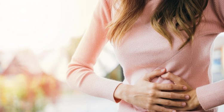 una donna che si tocca con entrambe le mani lo stomaco perché soffre di gastrite