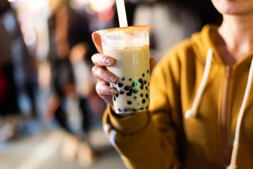 Bubble Tea: cos'è, ricetta, ingredienti e come farlo a casa 1 donna con felpa che ha in mano un bubble tea con cannuccia