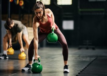una donna e un uomo si allenano in palestra con dei pesi