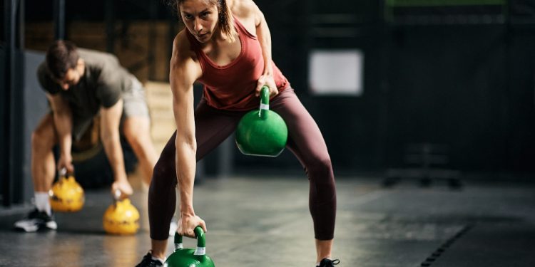 una donna e un uomo si allenano in palestra con dei pesi